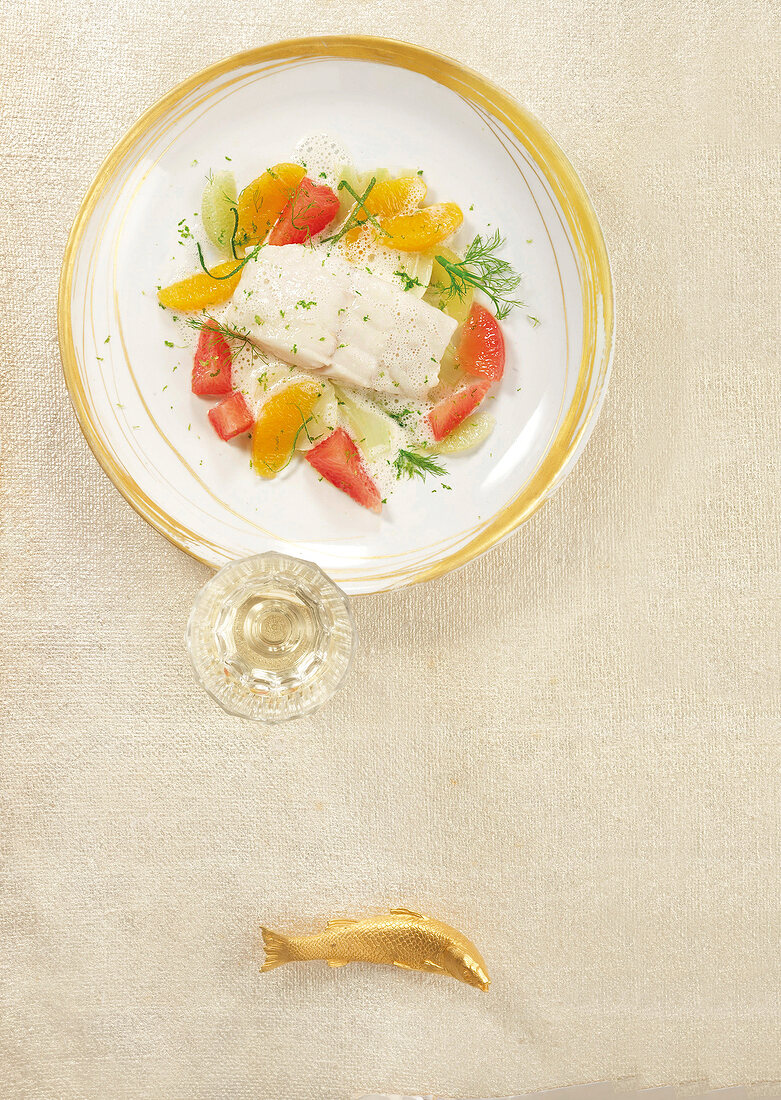Poached turbot with citrus fruits and fennel on plate, overhead view