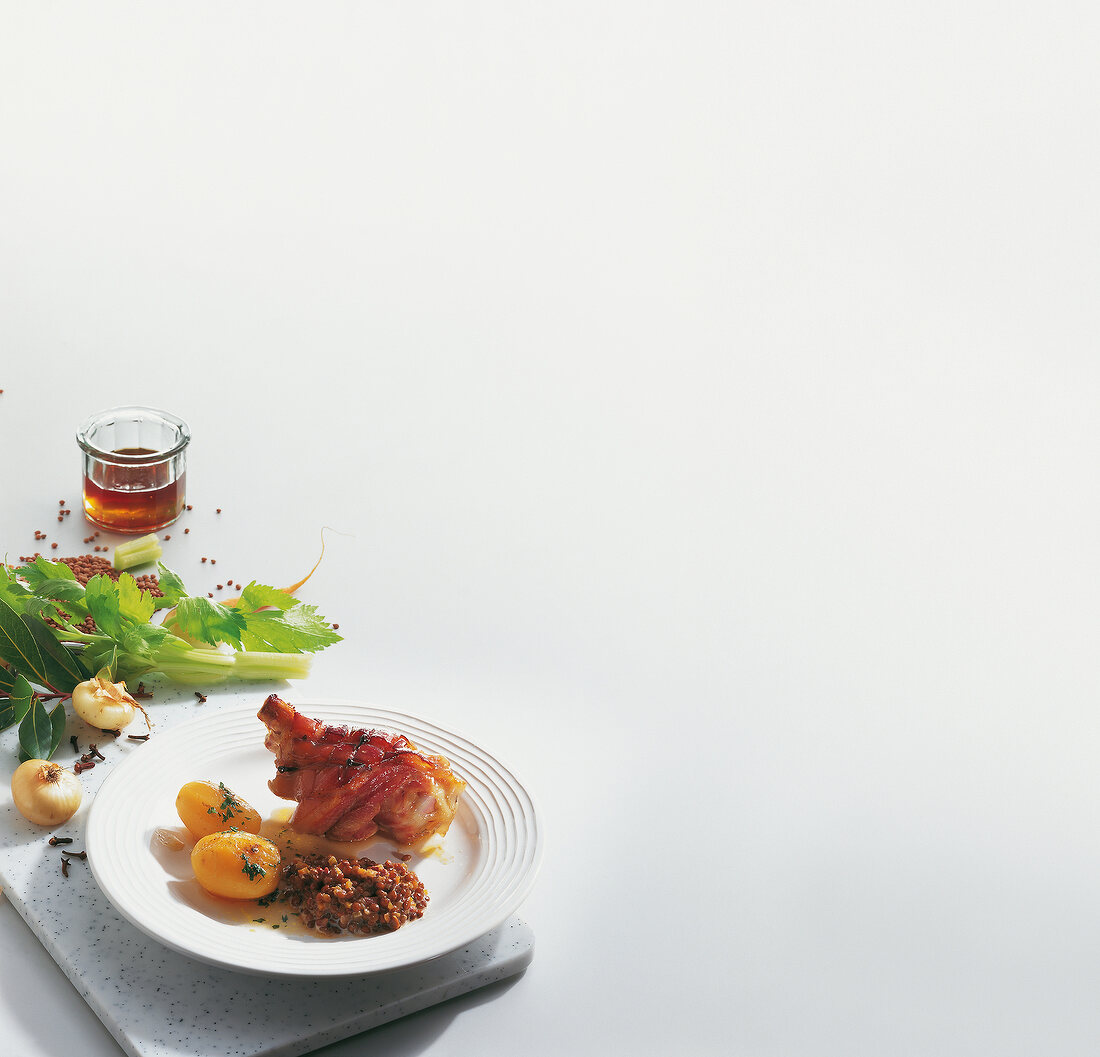 Pickled pork knuckle with lentils and potatoes on white background, copy space