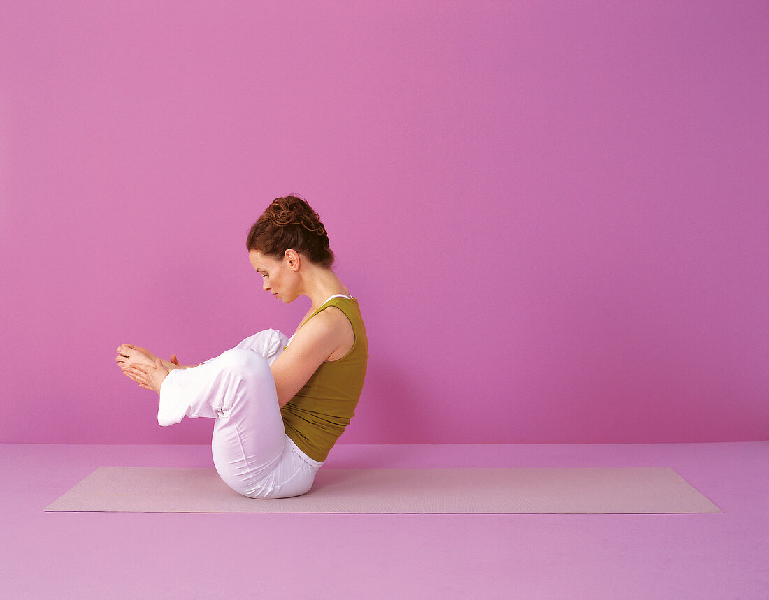 Pilates - Seal: Frau sitzt, Knie geöffnet, Hände an Füßen, Step 1