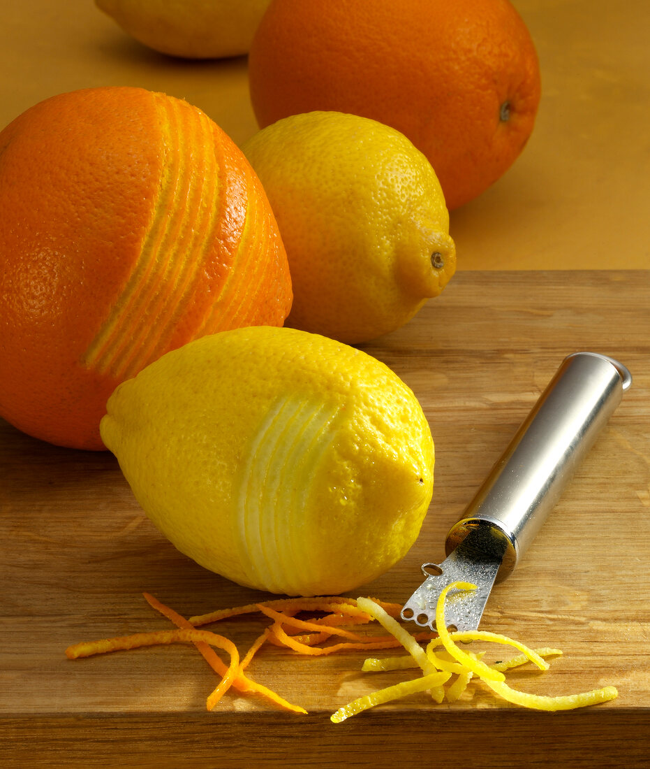 Strips of lemon and orange zest with peeler on table