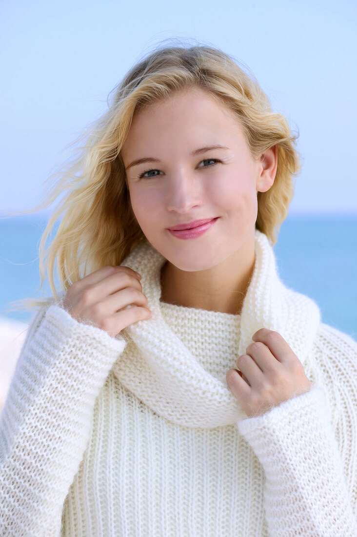 Portrait of pretty blonde woman wearing white turtleneck sweater, smiling