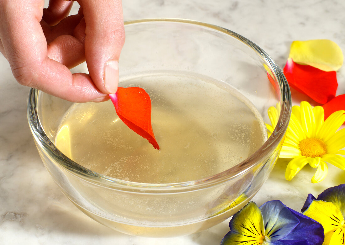 Flowers being dipped in bowl of liquid, step 1