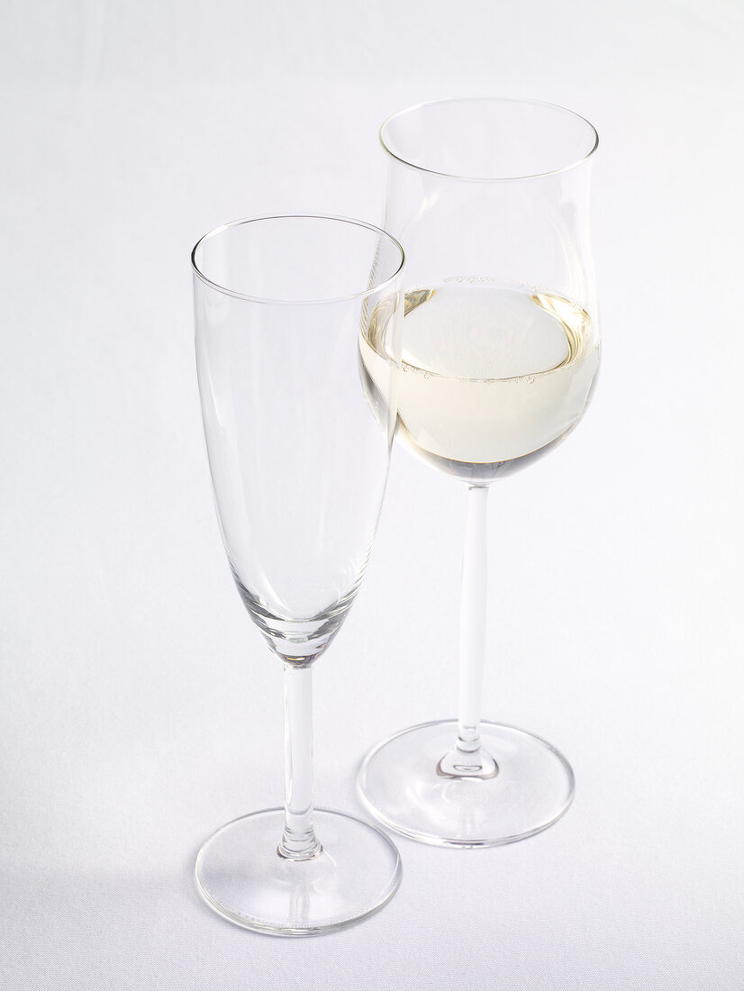 Empty champagne glass and white wine in wine glass on white background