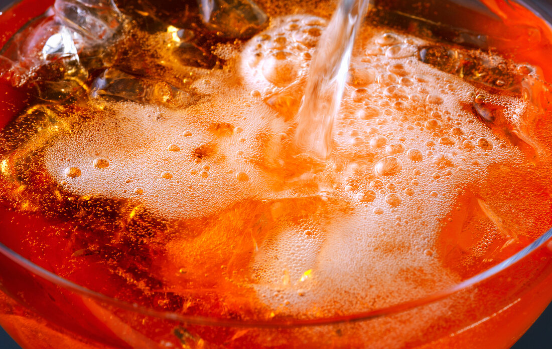 Mixschule, Close up: Oranges Getränk in 1 Glas gießen, Eiswürfel