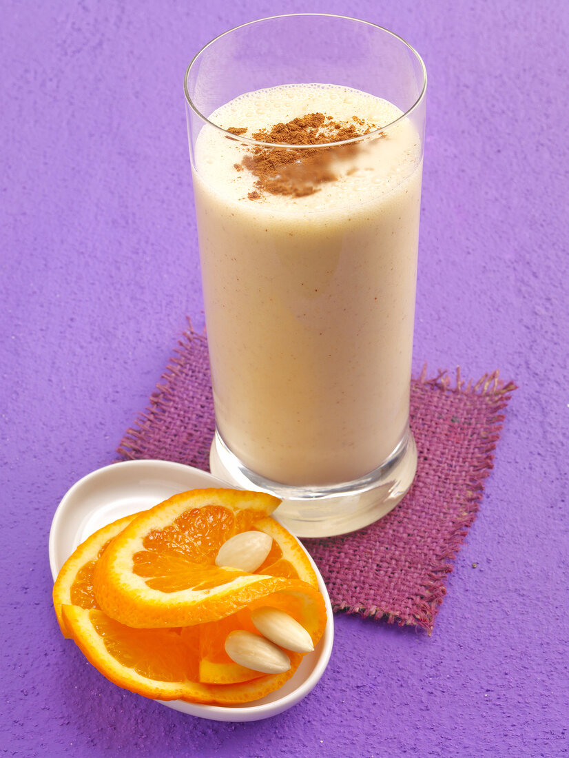 Almond and orange shake with cinnamon powder in glass