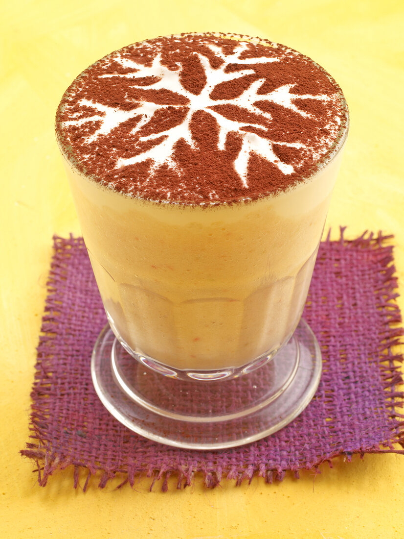 Coffee milk decorated with cocoa powder in glass