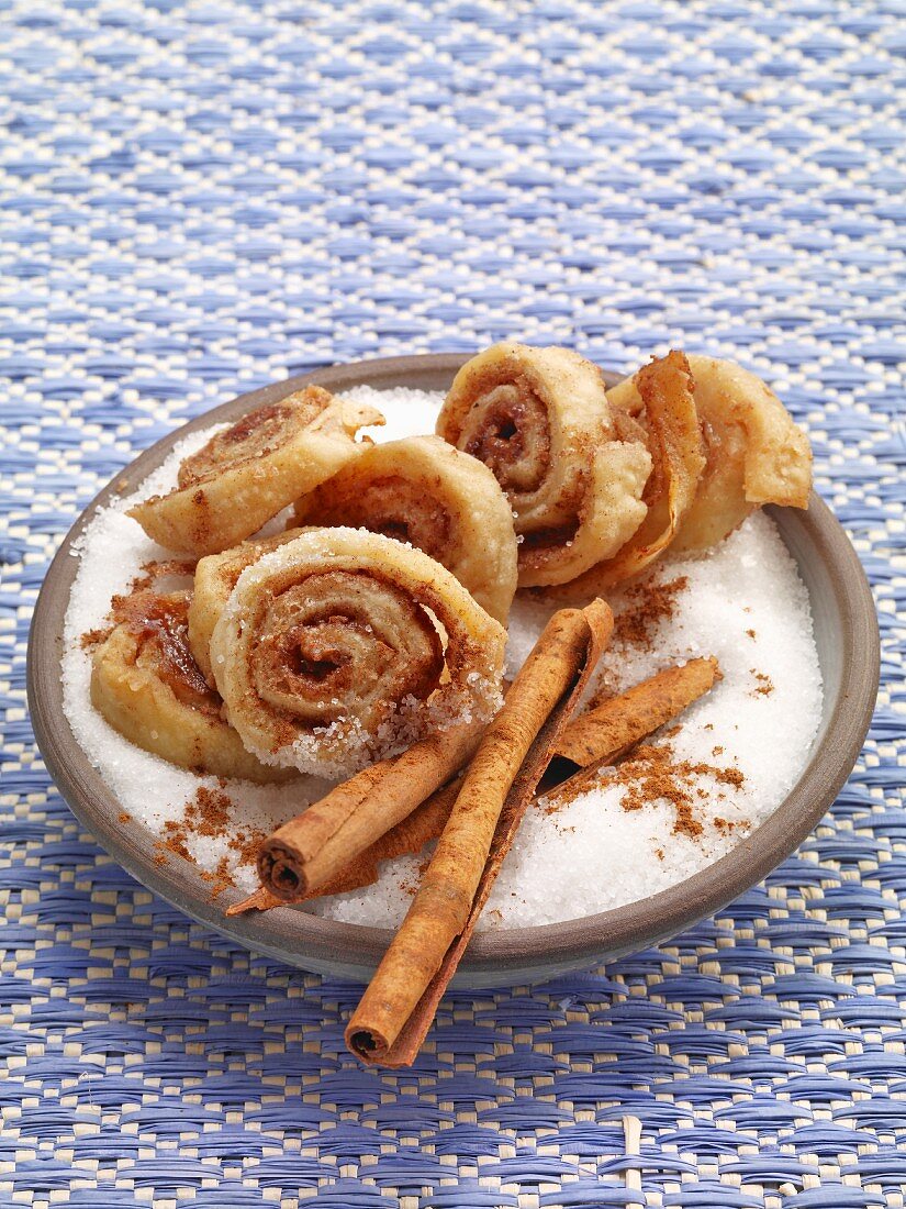Caramel pastries in a bowl with cinnamon sticks and sugar