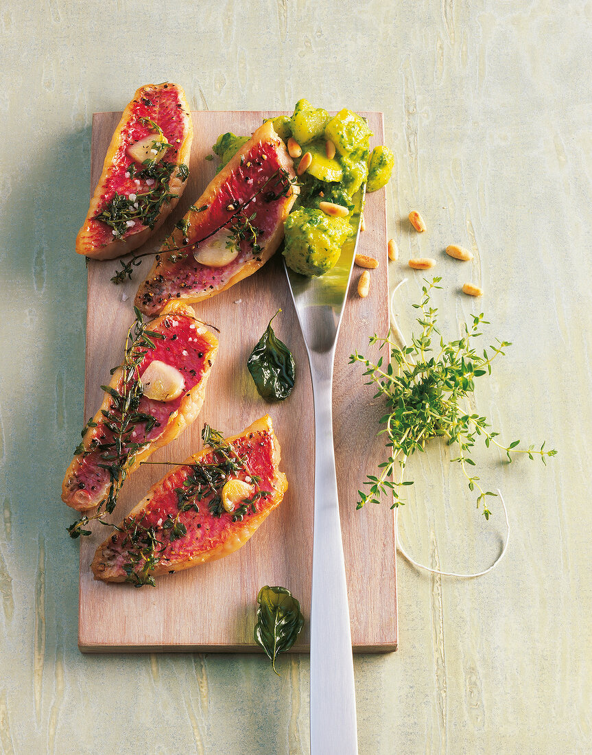 Red mullet with potato salad pesto on wooden board