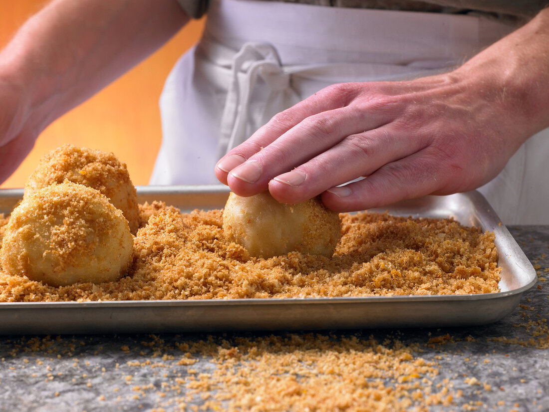 Dumplings being rolled in breadcrumbs, step 1