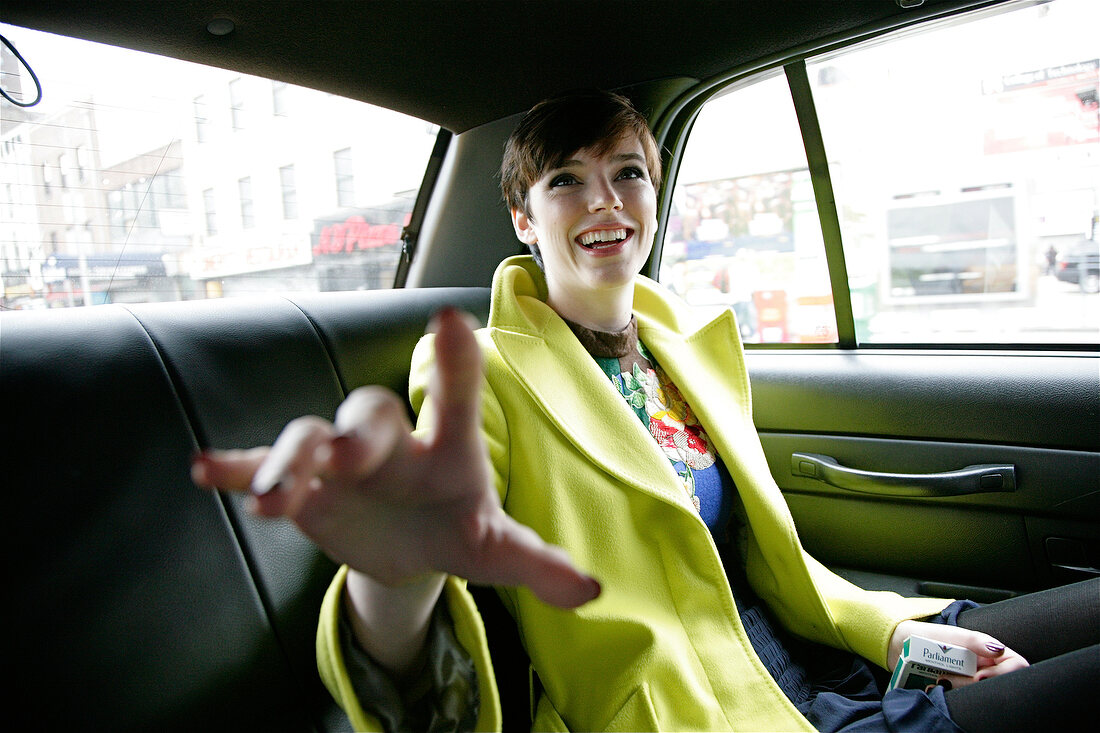 Ecstatic woman with short hair sitting in car looking away, laughing