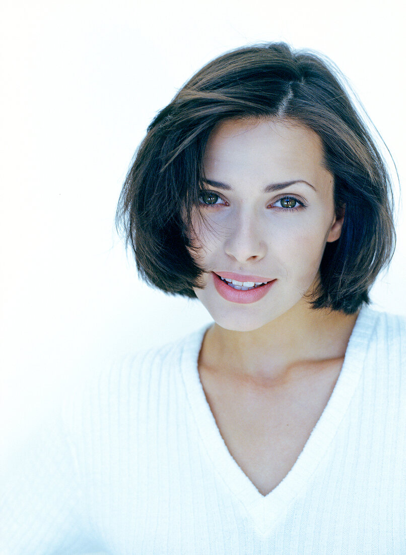 Portrait of beautiful brunette with bob woman wearing white sweater, smiling, close-up
