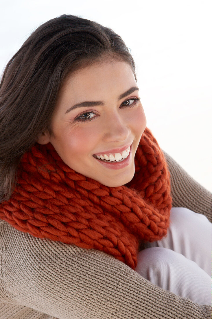 Portrait of beautiful woman wearing red woollen scarf, smiling
