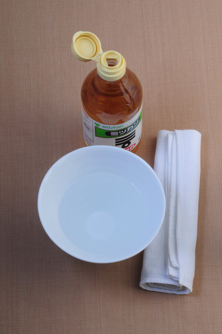 Vinegar water, dish and dish cloth on brown surface