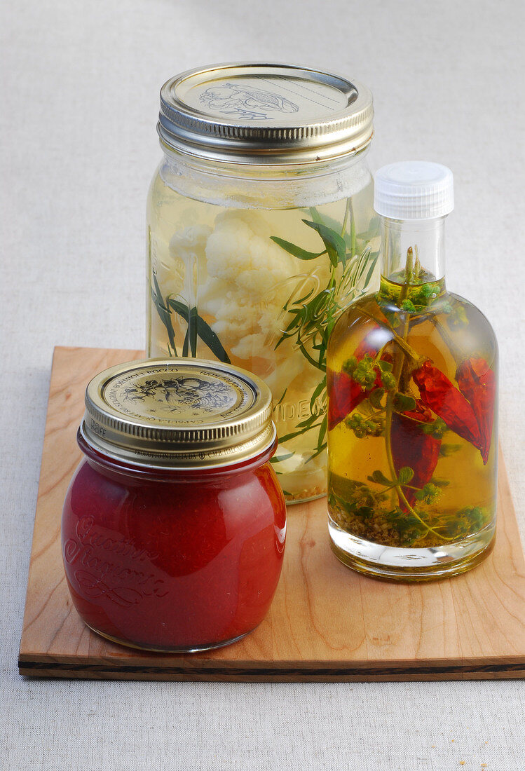 Jars with canned vegetables on wooden board