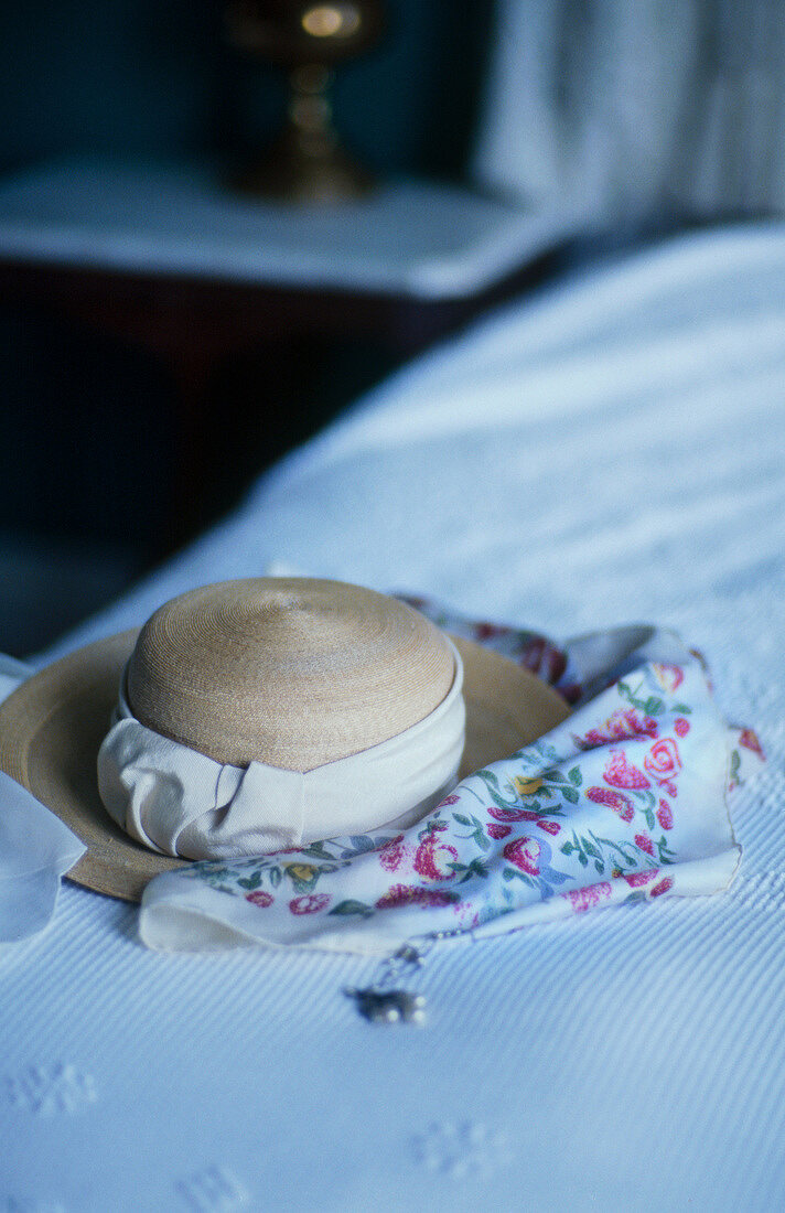 Straw hat with scarf on bed