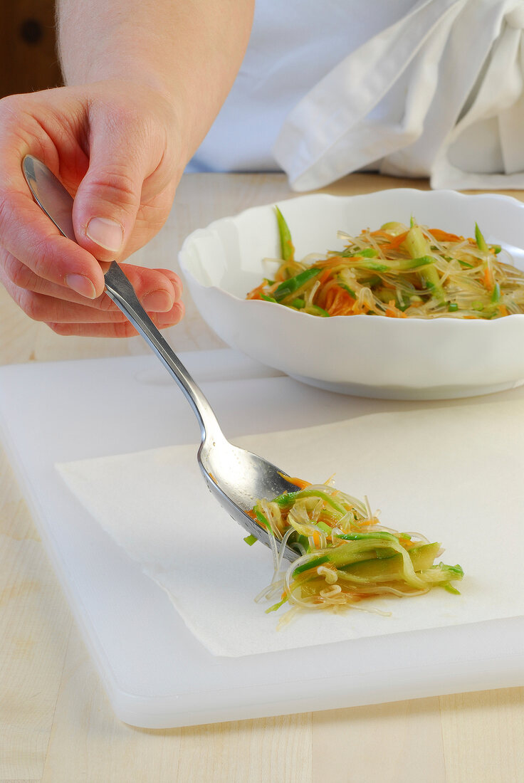 Glass noodle mixture being put on dough while preparing spring roll, step 1