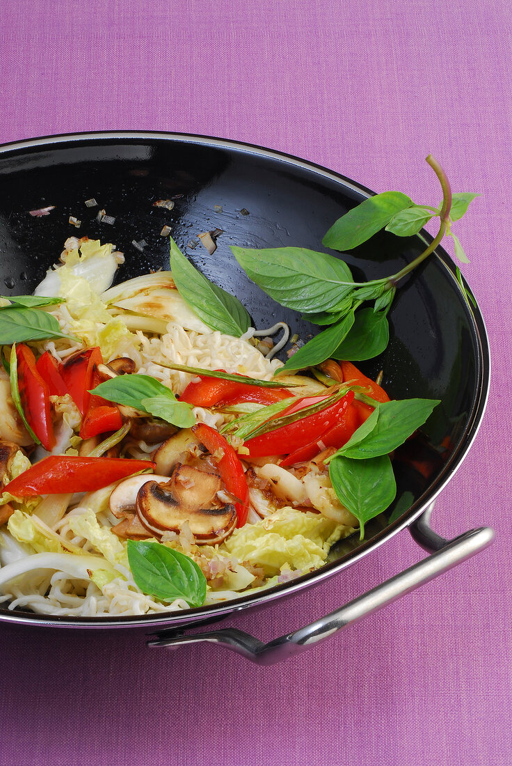 Fried egg noodles with vegetables and basil in wok