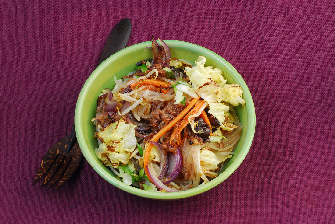 Bami goreng with noodles, ear mushrooms and beef in bowl