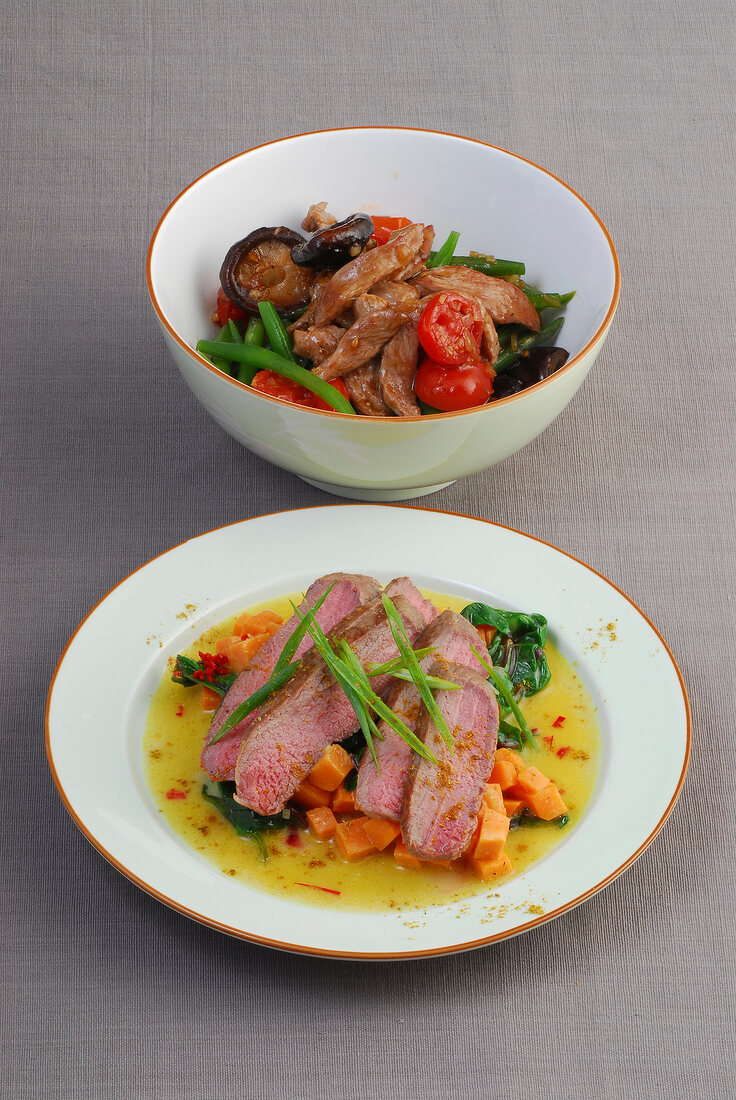 Bowl of lamb with beans and mushrooms and lamb with sweet potato and spinach on plate