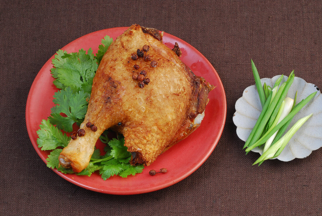 Fried duck garnished with szechwan pepper and coriander leaves on plate