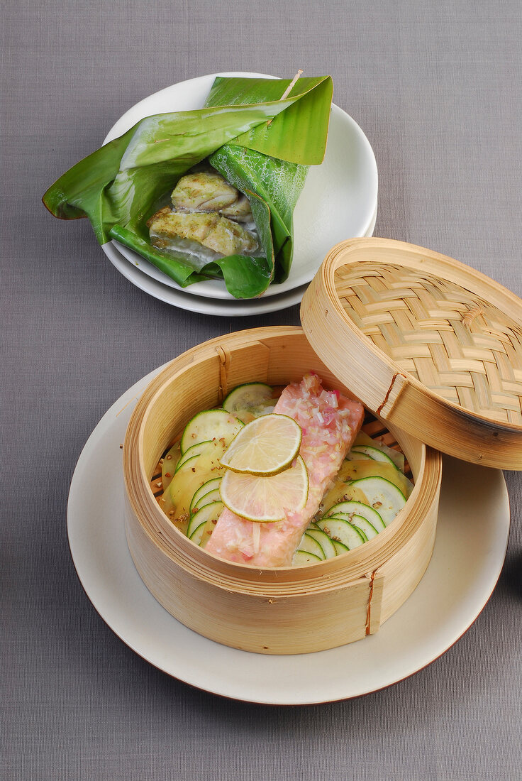Fish fillets in banana leaf and meat with zucchini in steamer basket