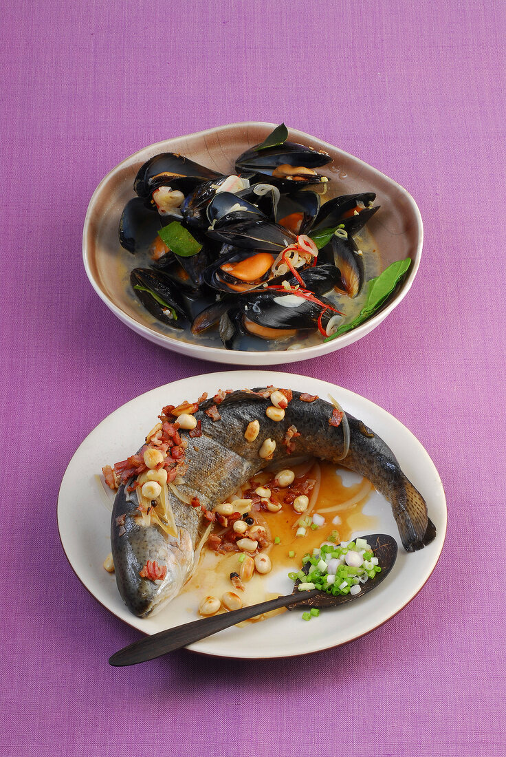 Bowl of mussels in lemon sauce and poached trout on plate