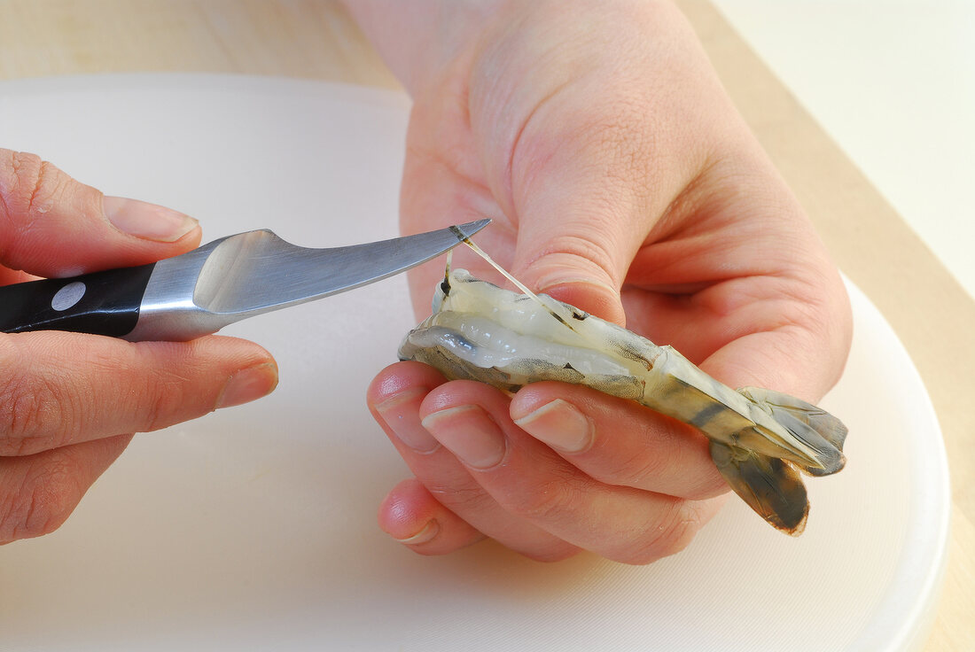 Close-up of shrimp being cut with knife while preparing crunchy prawns, step 1