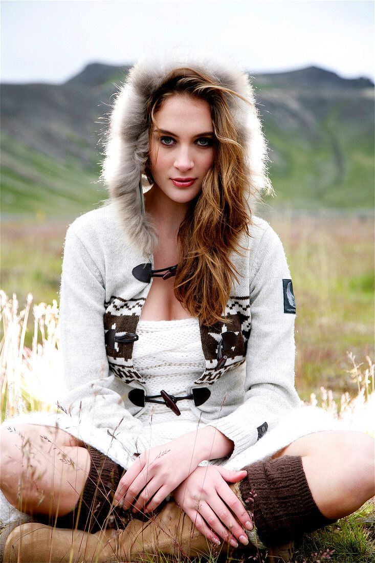 Portrait of beautiful gray eyed woman wearing knitted fur lined hood and boots, smiling
