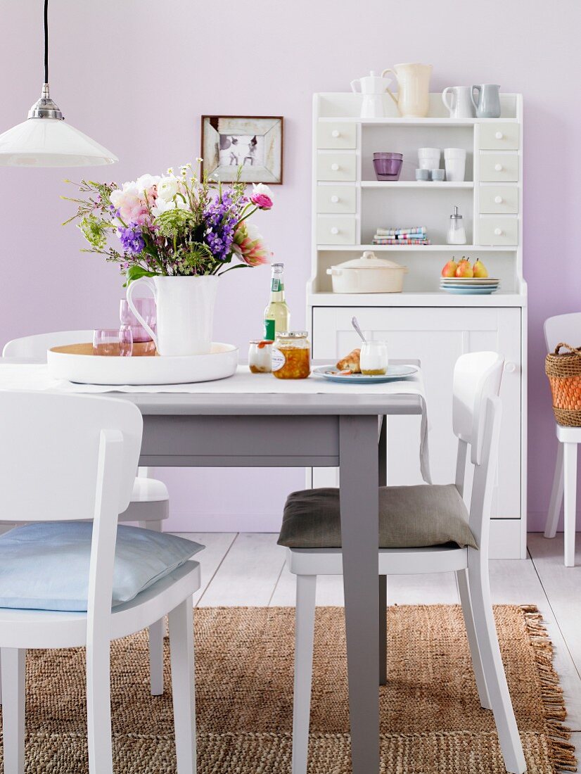 Tisch mit Blumenstrauss vor Buffetschrank in einem Esszimmer in Pastelltönen