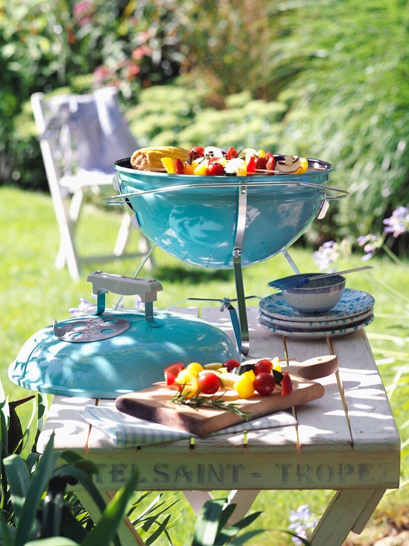 A portable barbecue on a wooden table in a summer garden