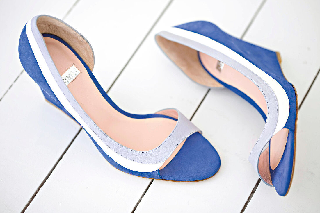 Blue pumps with wedge heels on white floor