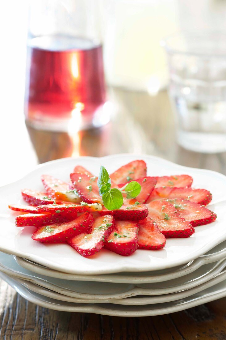 Sliced strawberry garnished with herb on plate