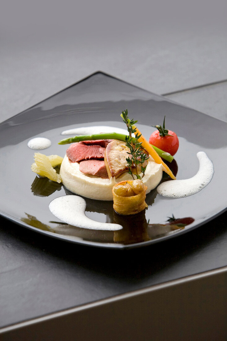 Fried foie gras with pigeon meat, celery puree and traminer grapes on plate