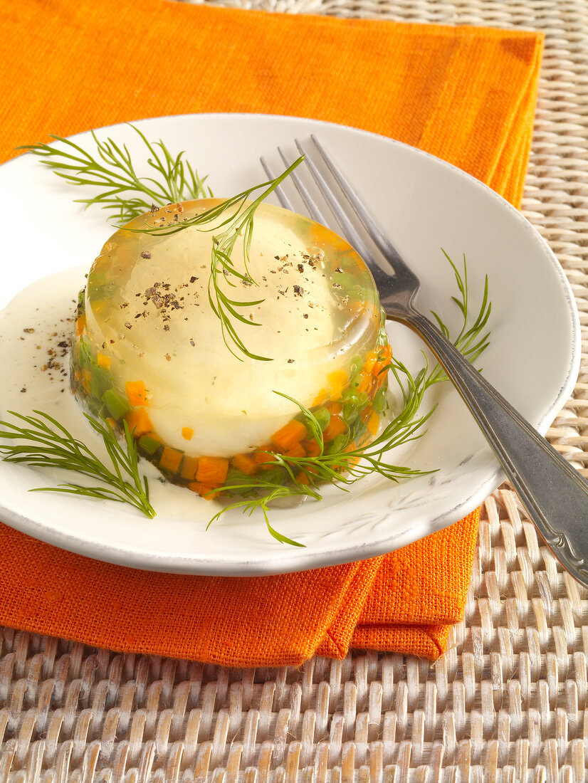 Eggs in wine jelly with carrots, beans and dill on plate