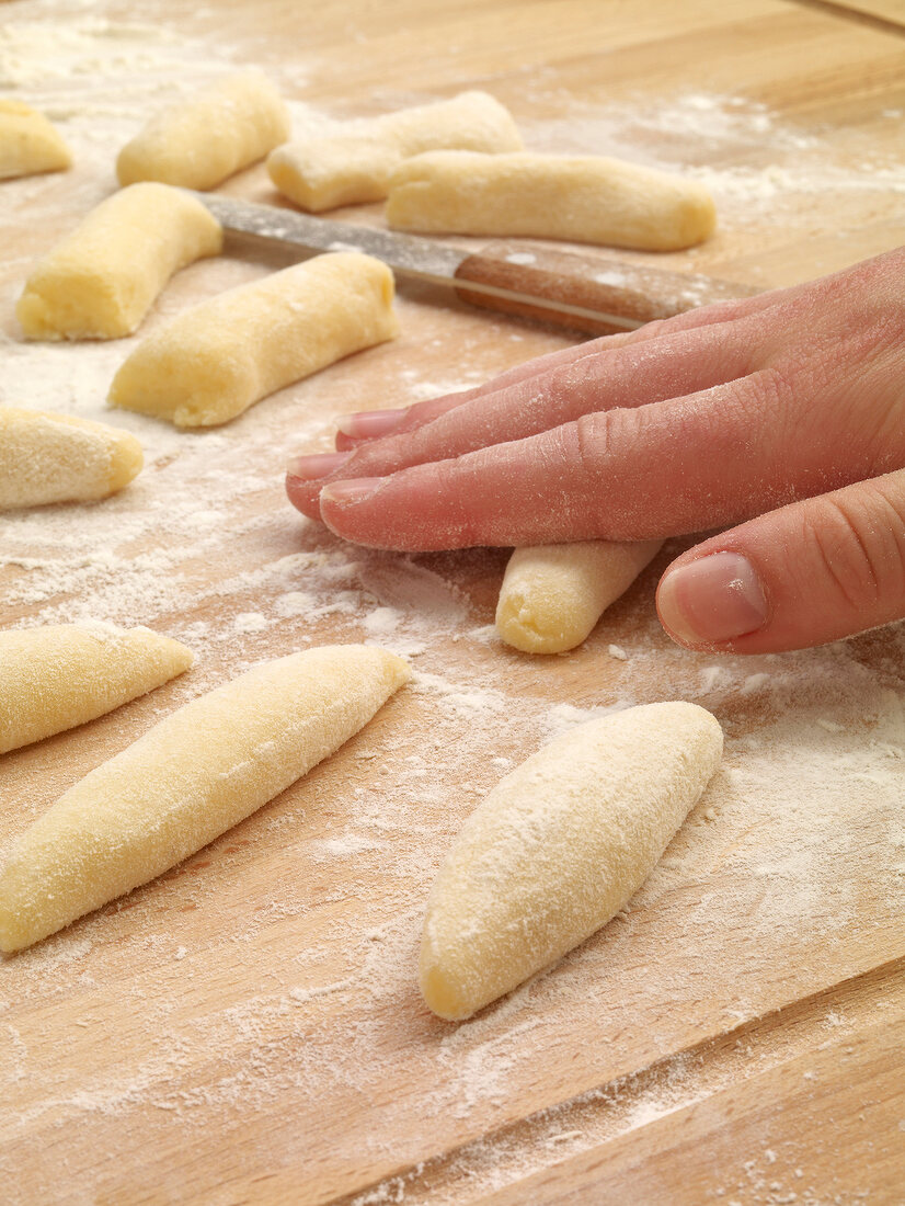 Potato dough being rolled in flour while preparing potato noodles, step 3