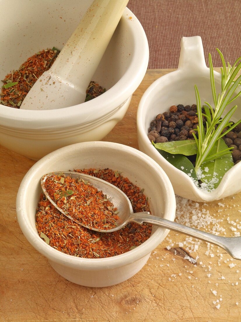 Seven spice mixture in mortar and pestle and in bowl, pepper with rosemary in cup