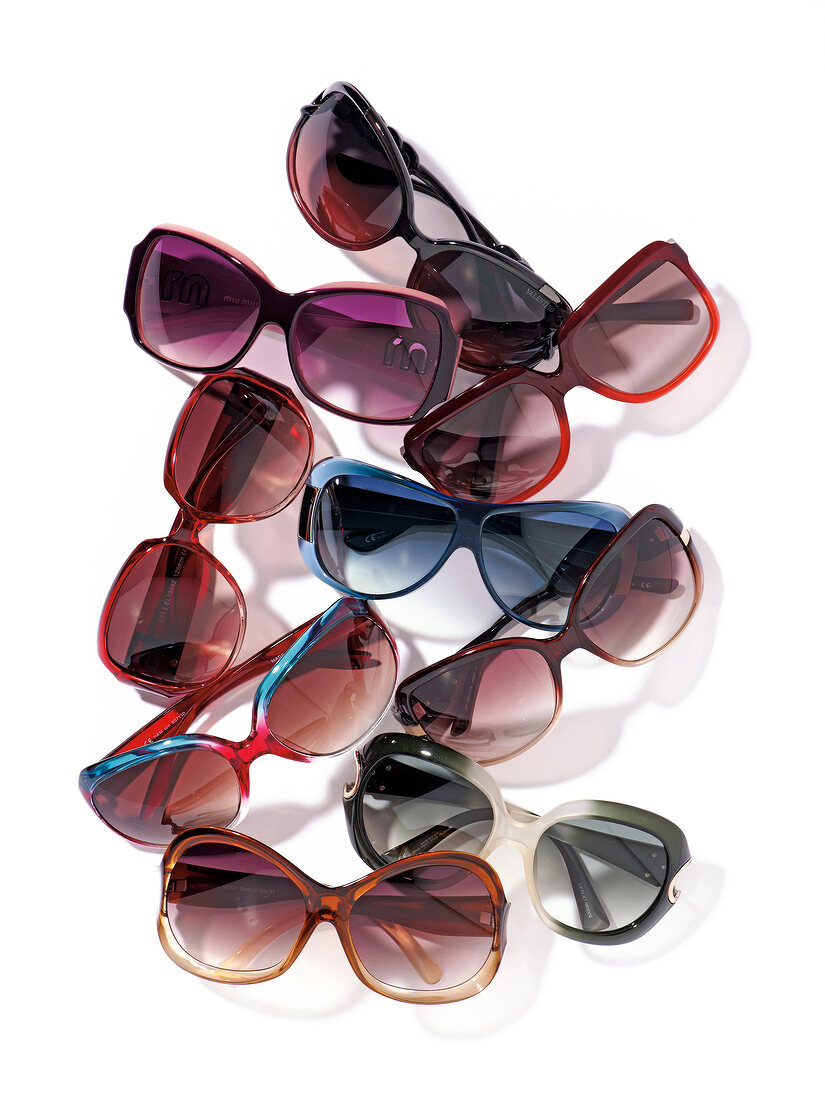 Various multi-coloured sunglasses on white background