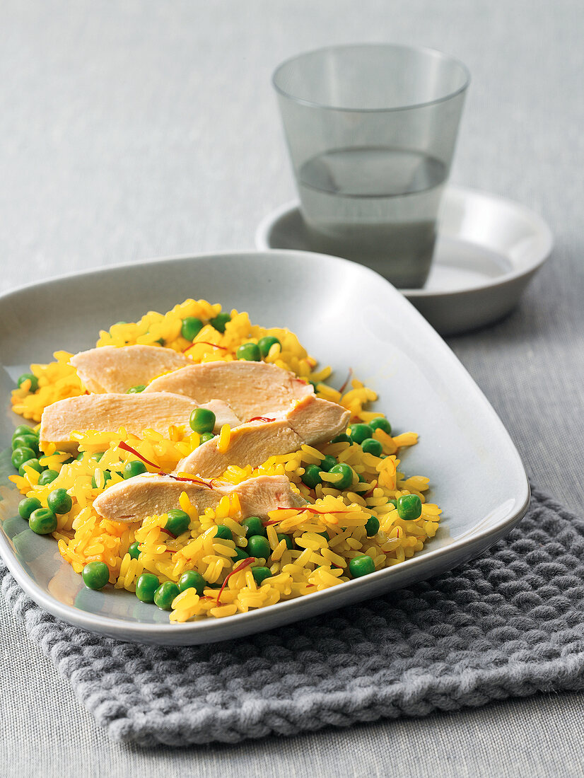 Saffron rice with chicken and peas on square plate
