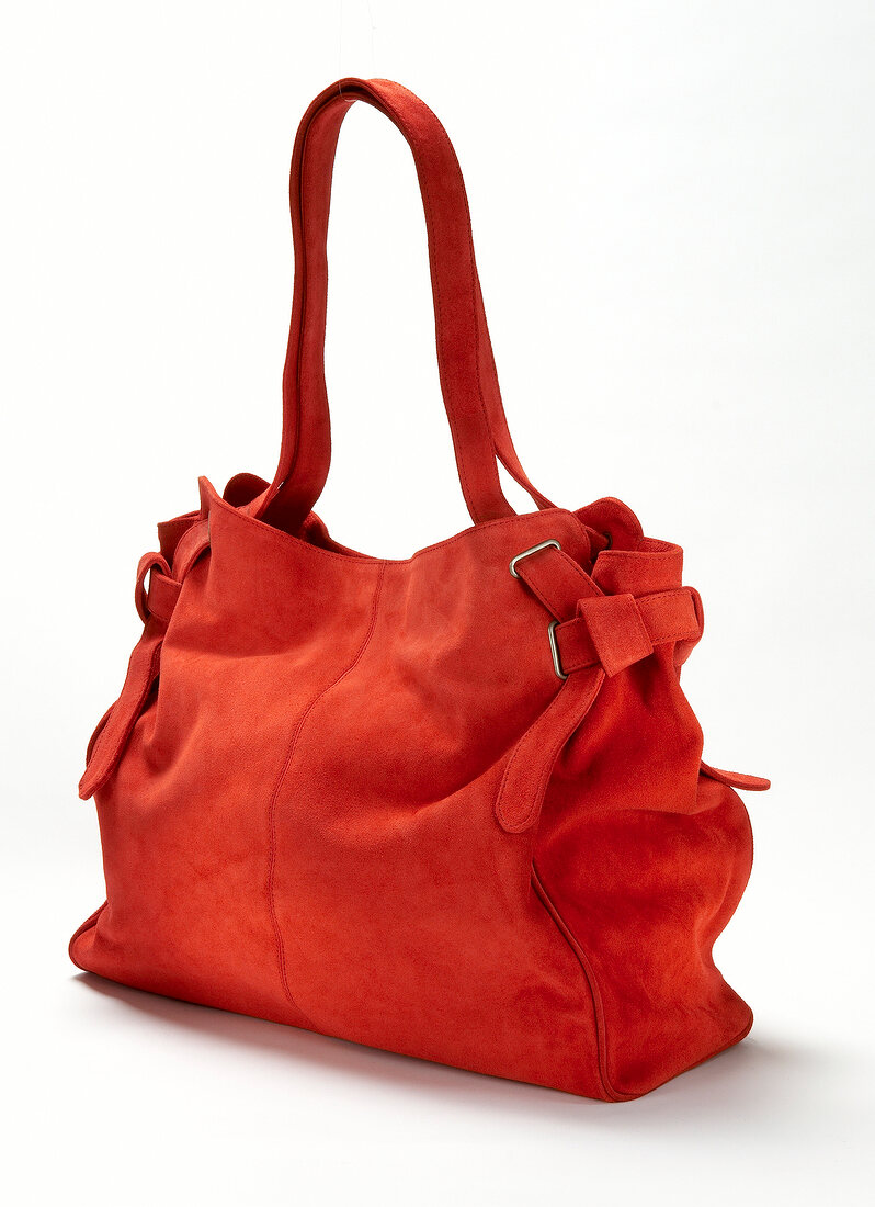 Close-up of red suede handbag on white background