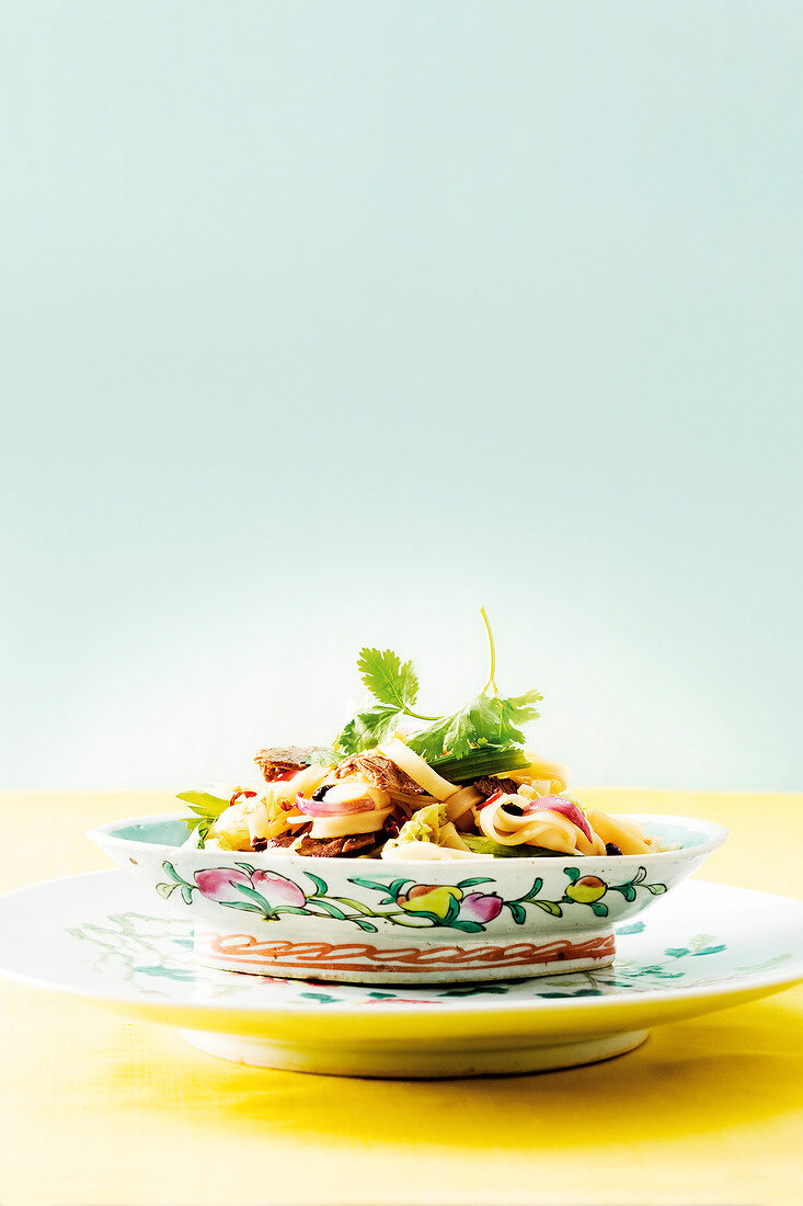 Rice noodles with beef, peanuts, black beans and cilantro in bowl