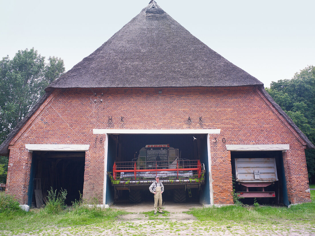 Man standing at the entrance of thatched farmhouse in Rieseby, Germany