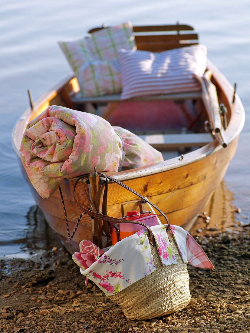 Boat on moored at shore with straw bag, blanket and pillow