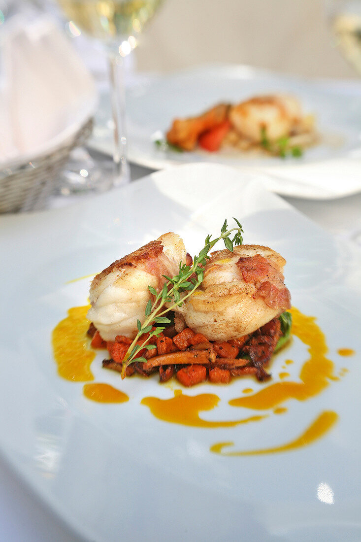 Monkfish medallions wrapped in bacon served with chanterelles on plate