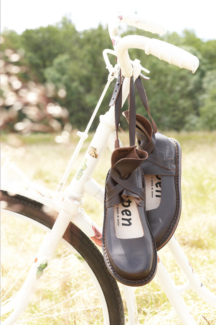 Pair of brown leather sandals on handlebars