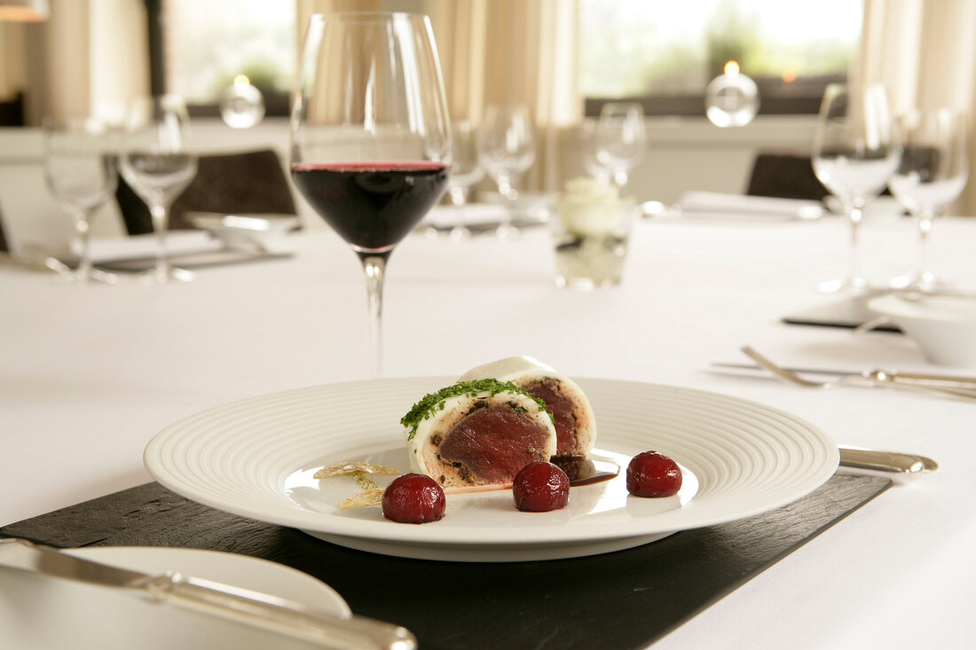 Steamed venison garnished with cherry tomatoes and herbs on plate