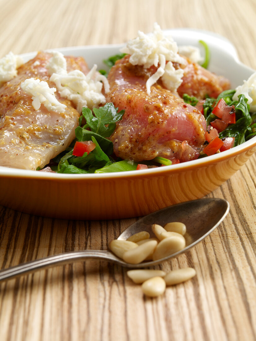 Goat cheese, chicken, pine nuts and herbs on serving dish