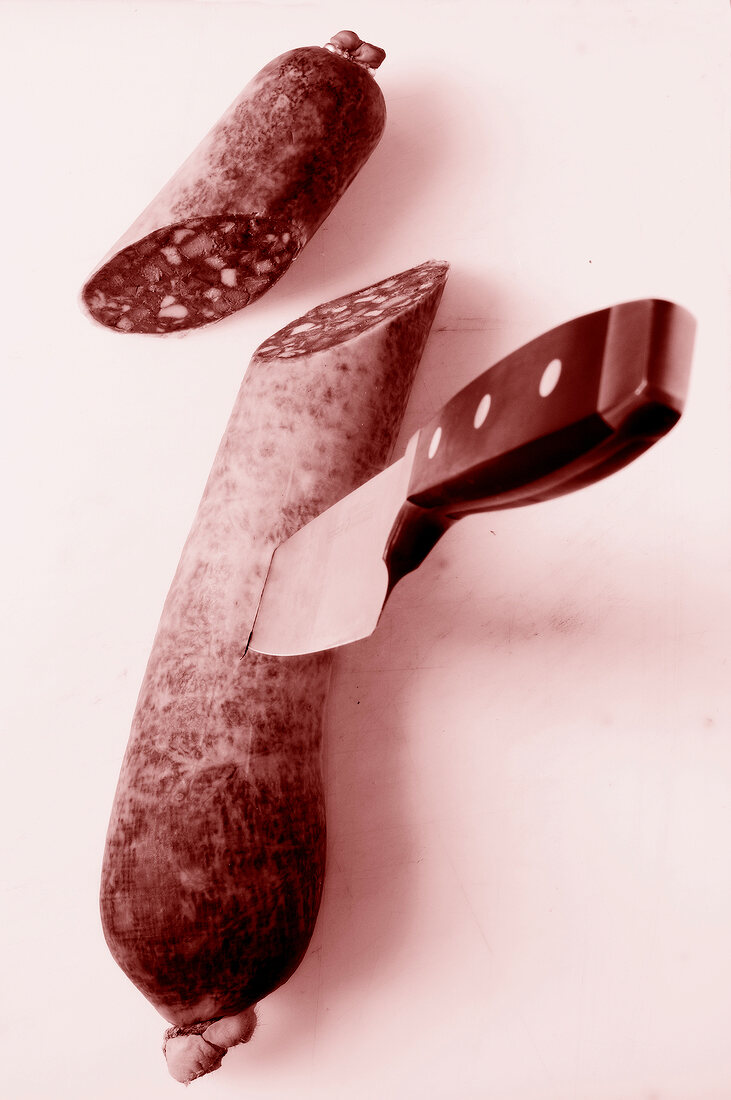 Knife with halved sausage on platform