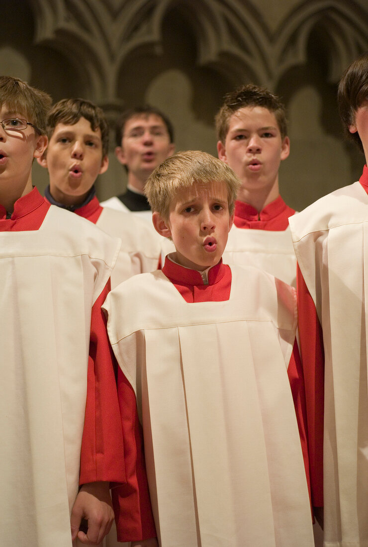 Choir boy's in red and white alter vestments singing in Cathedral