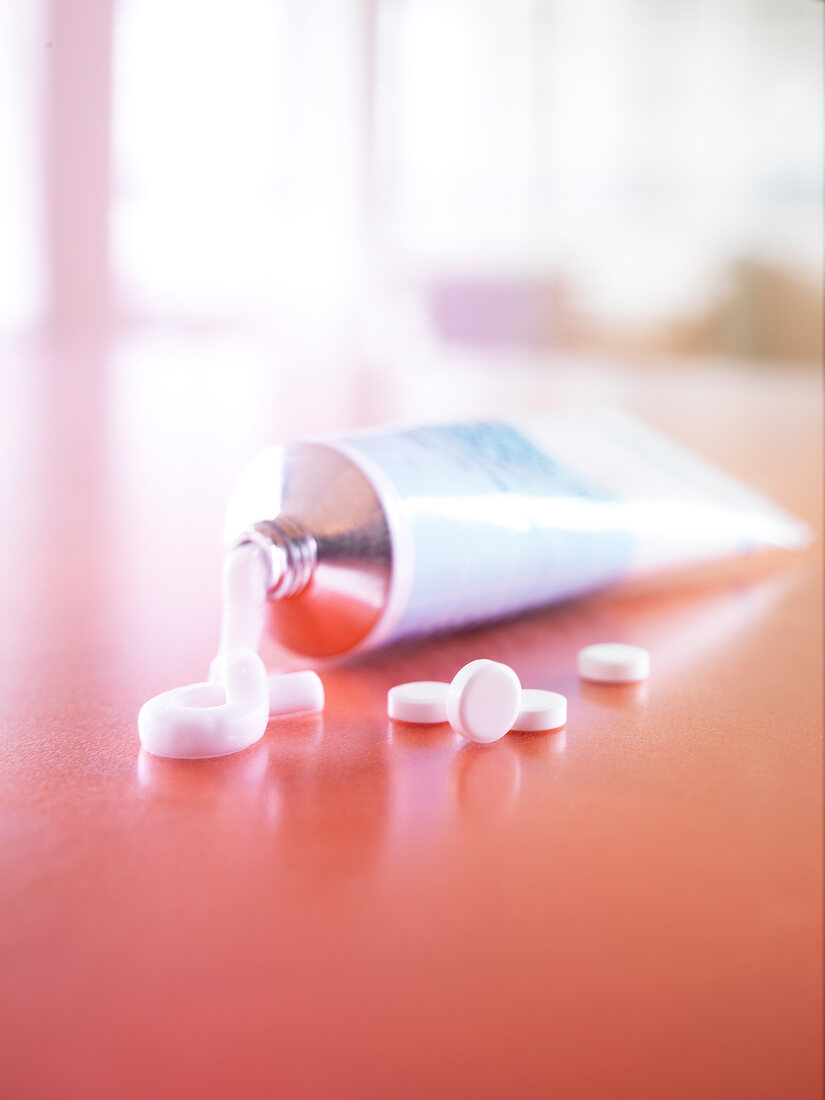 Close-up of squeezed cream and tablets on red surface