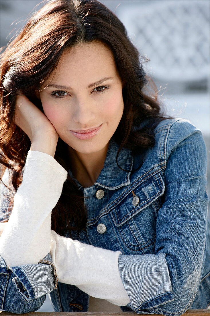 Portrait of beautiful woman with dark hair wearing denim jacket, smiling